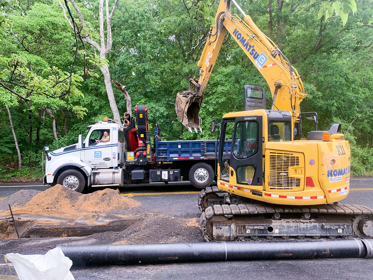 Roadside gas pipeline installation with excavator and backfilled trench